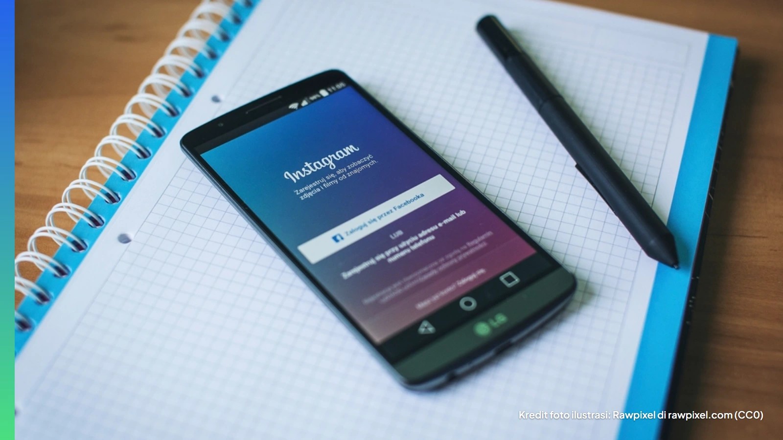 Ponsel menampilkan layar masuk Instagram di atas buku catatan dan pulpen
